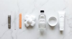 A collection of essential tools to **do a manicure** at home including a silver clipper and glass file on marble.