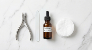 Essential nail care tools including sanitized clippers, a glass file, and rubbing alcohol for proper hygiene.