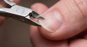 Close up of trimming a hangnail safely using a sanitized cuticle nipper to avoid injury.