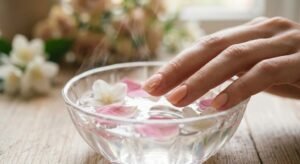 Safe acrylic nail care using the acetone soak method with flower petals for natural nail protection.