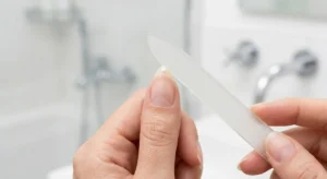 A focused close-up shot showing a person checking the symmetry of an almond nail with a center mark dot.
