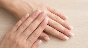 A top-down comparison of sharp square nails and softly rounded squoval nails on a light wood background.